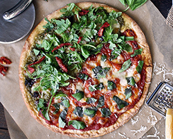 A photograph of a pizza from above, with a pizza slicer and a cheese shredder in frame