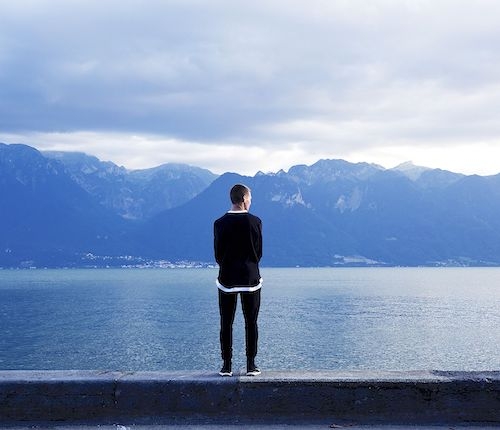 A man looking out over blue lake